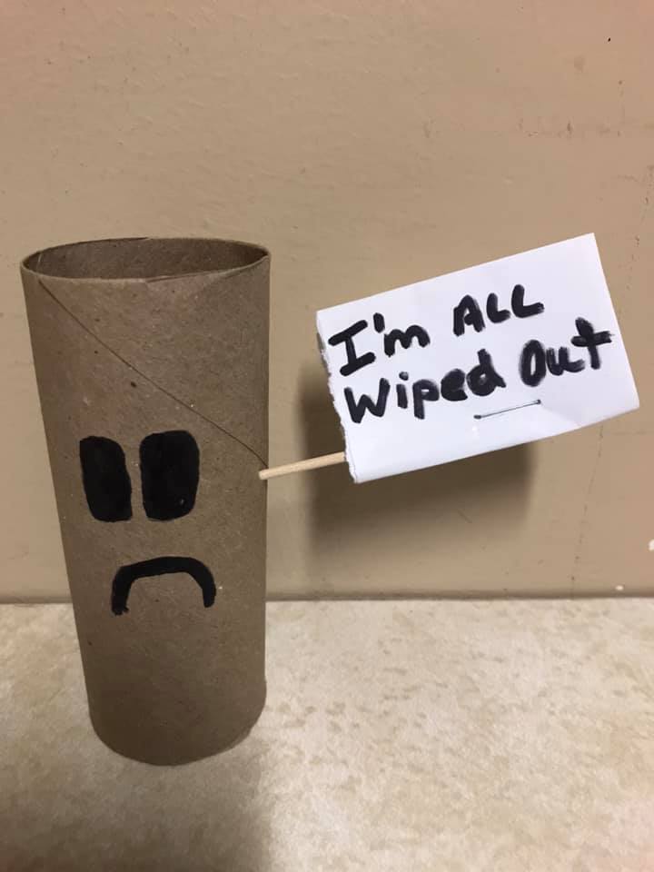Empty toilet paper tube with a frown, sign saying 'I'm all wiped out'